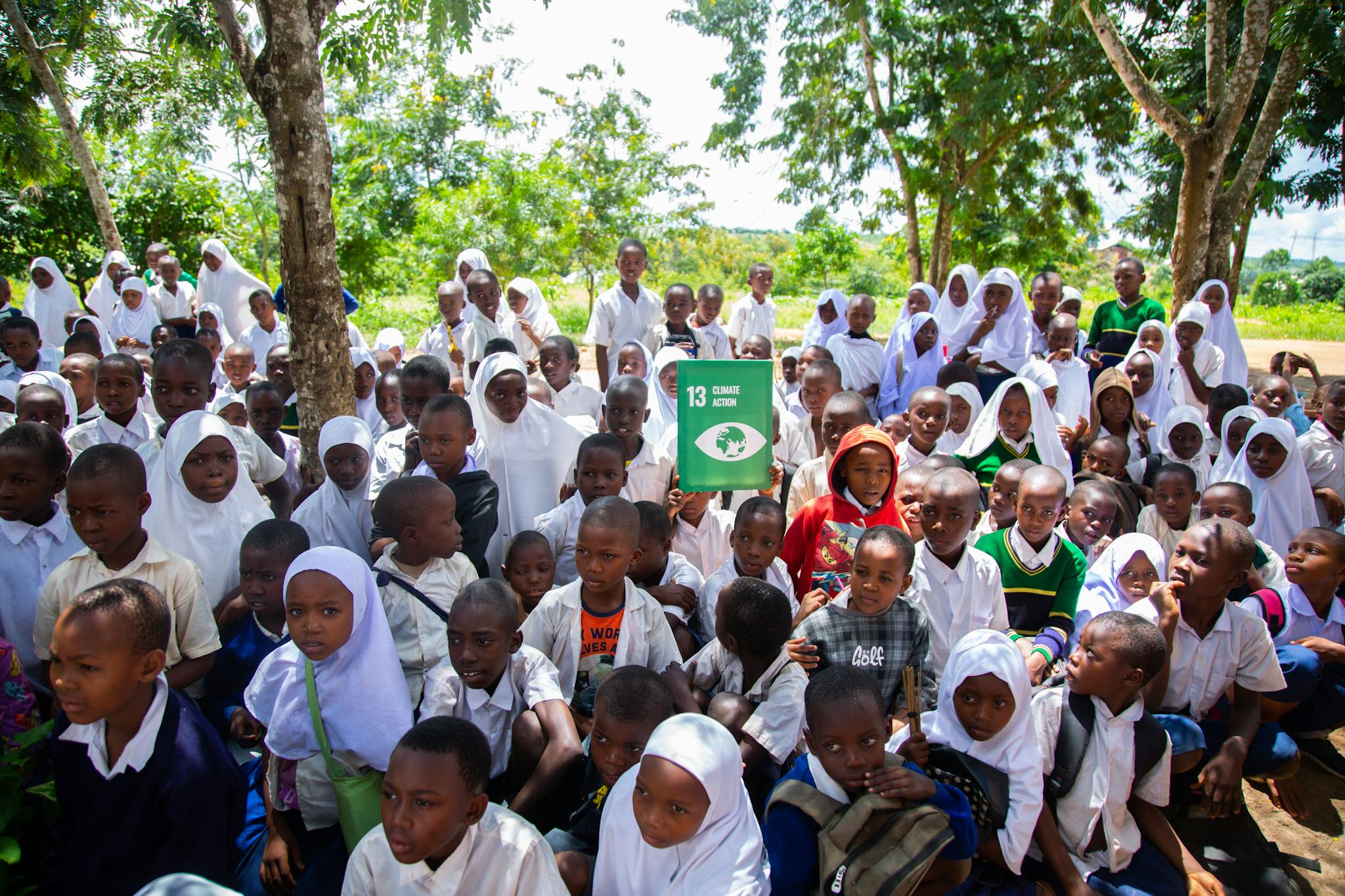 Large group of children wearing uniforms outdoors, promoting climate action