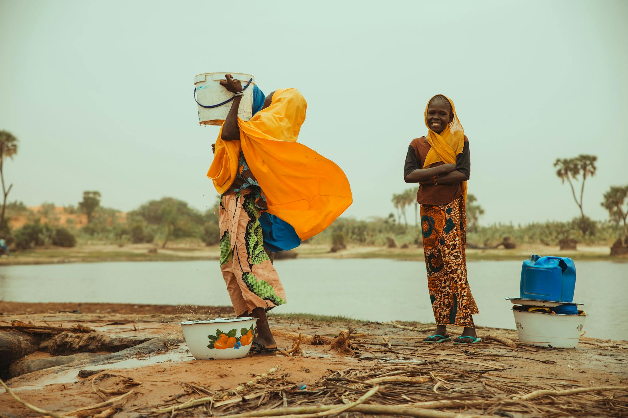 Two African girls collecting water at a lakeshore, depicting everyday life in rural Africa.